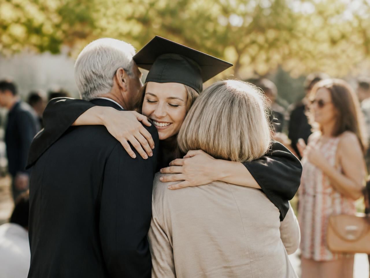 Graduate hugging family at an outdoor graduation party in Greater Houston
